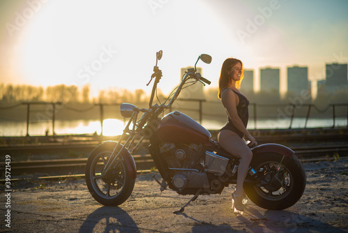 Red-haired woman in sexy lingerie in high heels sits on a motorcycle