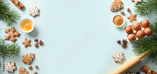 Christmas banner with cookies, different spices, eggs, rolling pin and ingredients for cooking on light blue background. Copy space. View from above.