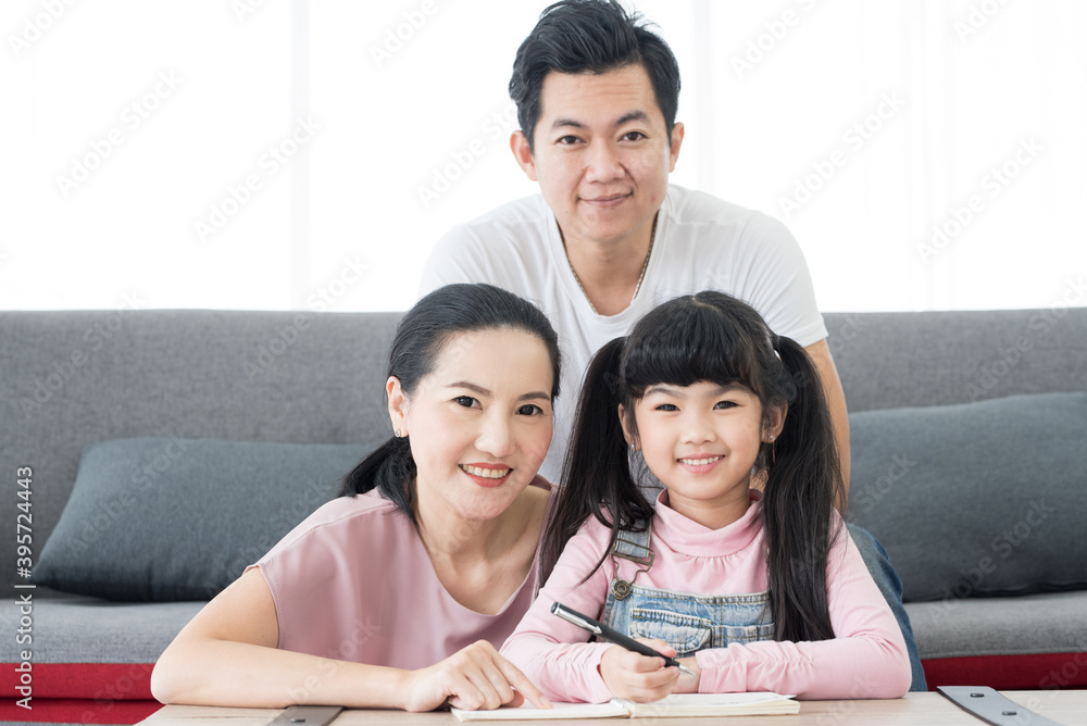 Education concept.Portrait enjoy happy smiling love asian family father and mother with little asian girl learning and writing in book with pencmaking homework at home. Education concept.Portrait enjoy happy smiling love asian family father and mother with little asian girl learning and writing in book with pencmaking homework at home.