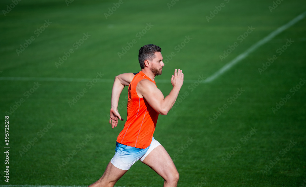Obraz premium athletic muscular man running on racetrack at outdoor stadium, success