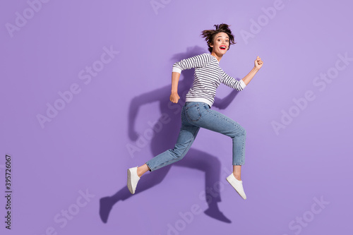 Full length photo of lovely cute young woman wear casual outfit jumping running straight isolated violet color background