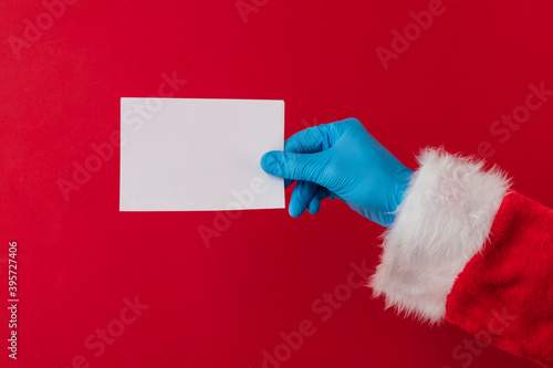 Santa hands wearing blue PPE protective gloves holding a blank card