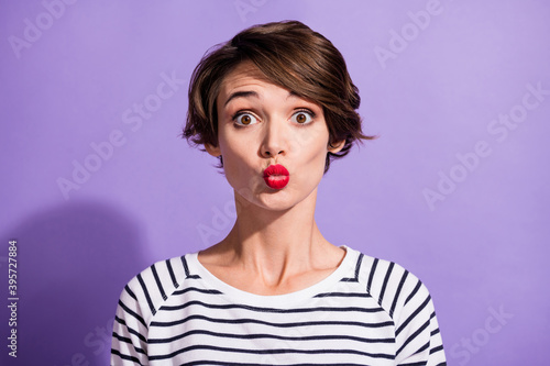 Portrait of sweet flirty short brunette hairdo girl blow kiss wear stripped pullover isolated on violet color background © deagreez