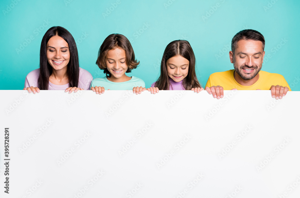 Photo portrait of big family with little kids holding big white paper sheet with copyspace isolated on vivid teal colored background Photo portrait of big family with little kids holding big white paper sheet with copyspace isolated on vivid teal colored background