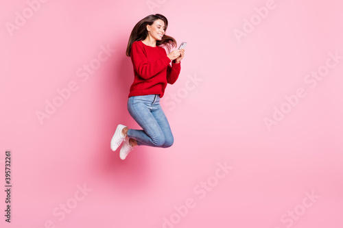 Full length body size portrait of pretty female student jumping high keeping using smartphone isolated on pink color background