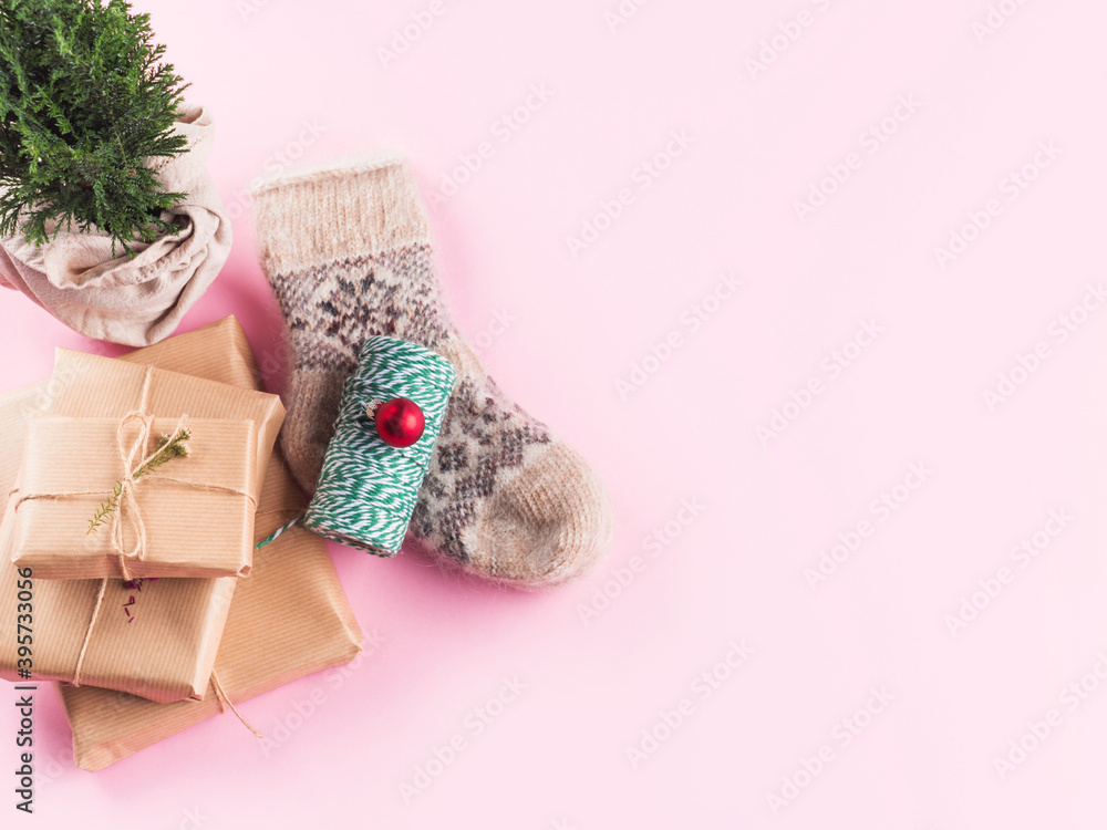 Minimal Christmas flat lay on pink with cozy socks, stack of gift boxes, green twine and wrapped plant tree. Top view Minimal Christmas flat lay on pink with cozy socks, stack of gift boxes, green twine and wrapped plant tree. Top view