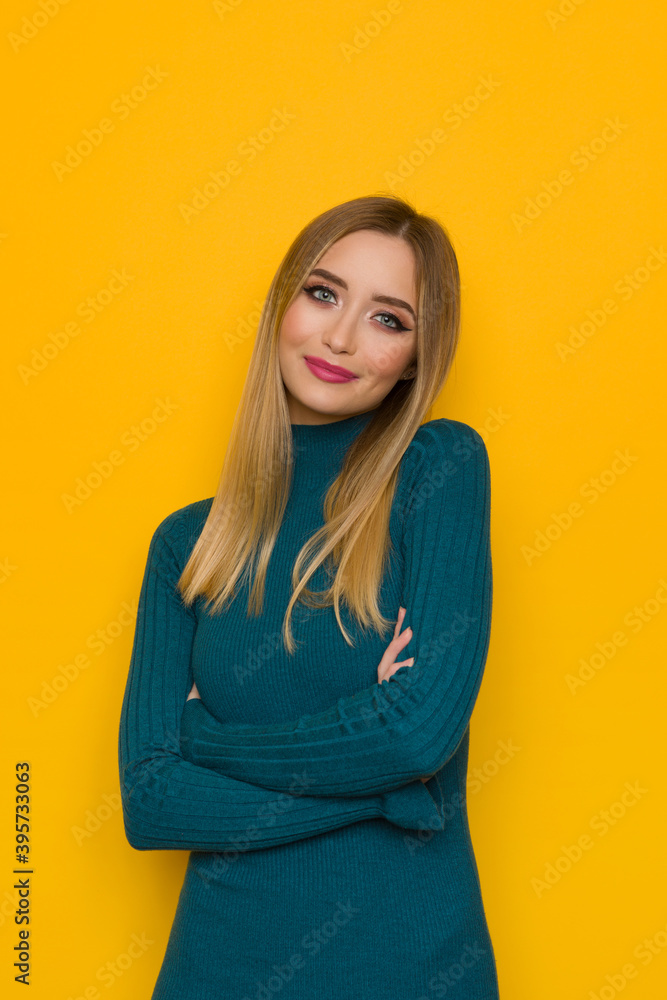 Fototapeta premium Beautiful Young Woman In Teal Fitted Dress Is Posing With Arms Crossed