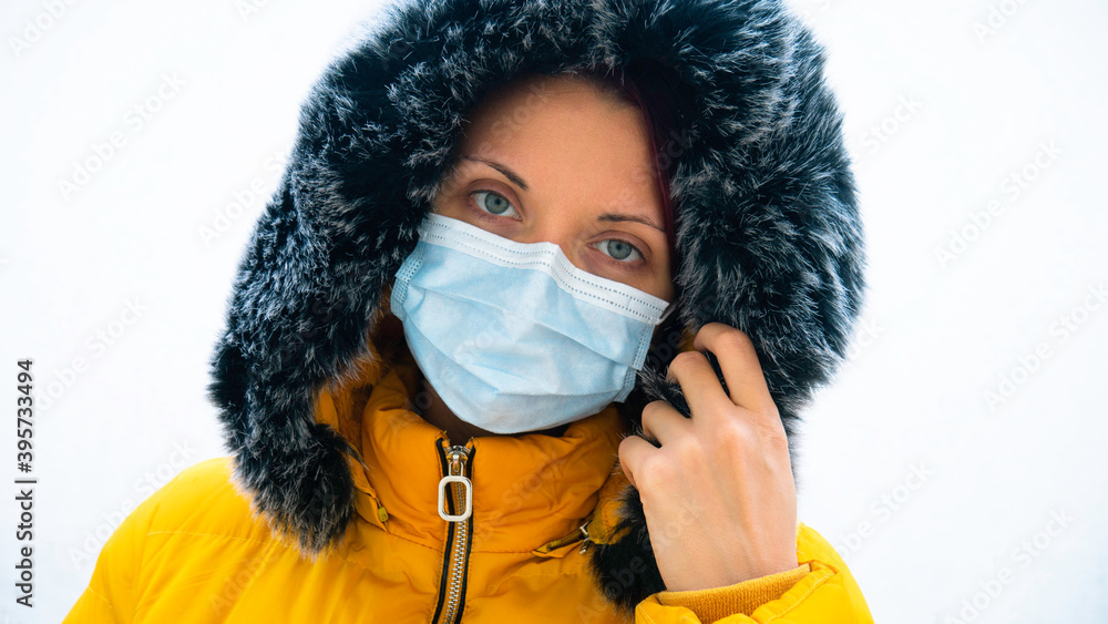 Woman with in a yellow jacket with a fur hood and a medical mask. Coronavirus disease 2019, COVID-19 or 2019-nCoV concept. Woman with in a yellow jacket with a fur hood and a medical mask. Coronavirus disease 2019, COVID-19 or 2019-nCoV concept.