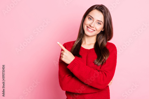 Photo portrait of pretty female student smiling pointing on empty space with finger wearing red sweater isolated on pink color background