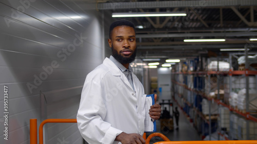 фотографія Portrait of african engineer in white coat holding clipboard and looking at came