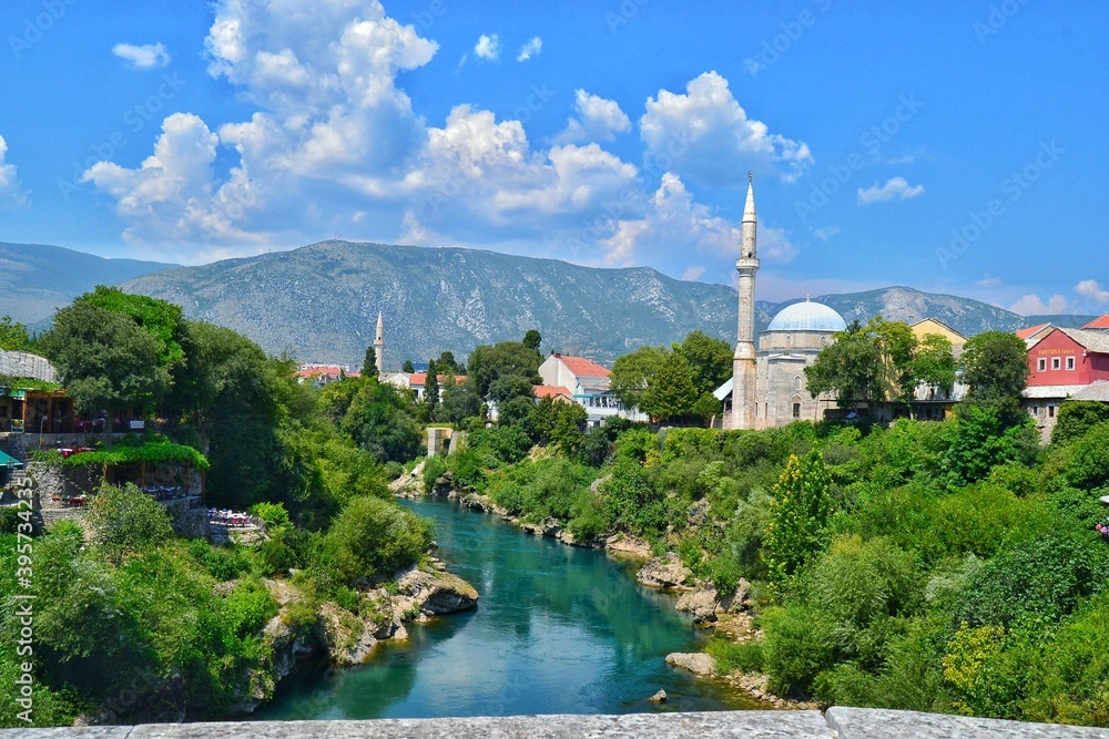 Green city of Bosnia and Herzegovina. City of Mostar, Bosnia and Herzegovina. Green Neretva River, blue sky. mosque and minaret and colorful city.