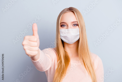 Close-up portrait of pretty healthy blonde girl wearing safety mask giving thumbup isolated on gray color background