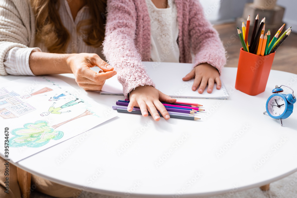 cropped view of girl drawing pictures with colorful pencils while visiting psychologist cropped view of girl drawing pictures with colorful pencils while visiting psychologist
