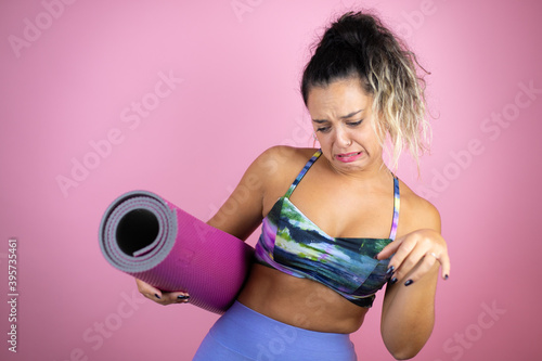 Young beautiful woman wearing sportswear and holding a splinter over isolated pink background disgusted expression, displeased and fearful doing disgust face because aversion reaction.Annoying