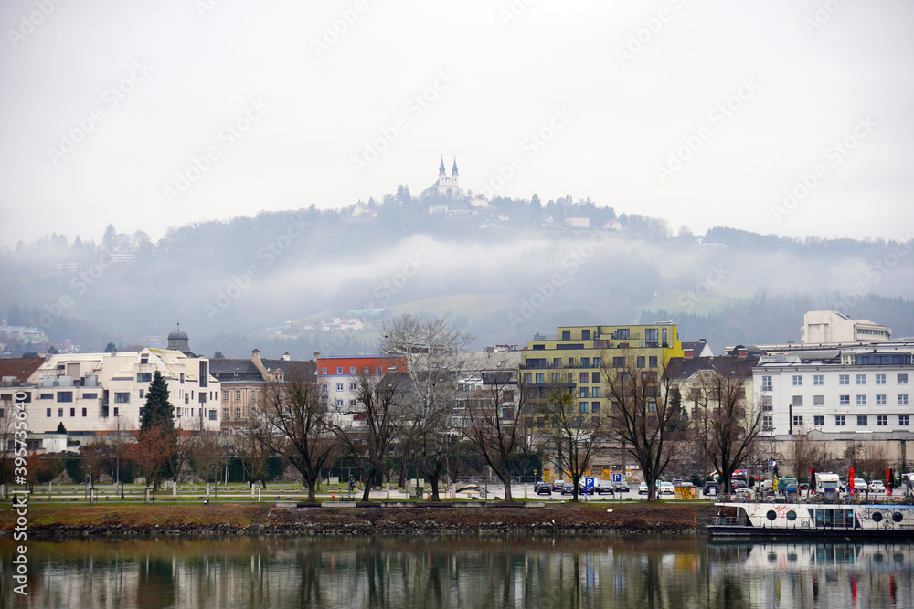 Pöstlingberg mit barocker Wallfahrtskirche über der Stadt Linz gesehen im Winter  auf einem nebligen Tag