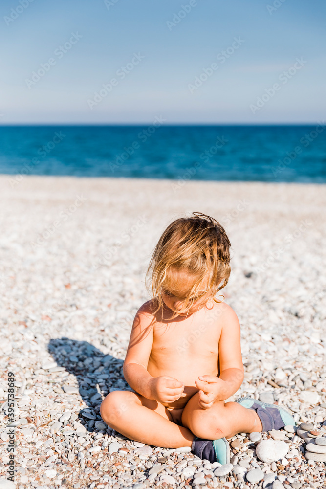 Toddler girl playing with pebbles on beach Toddler girl playing with pebbles on beach
