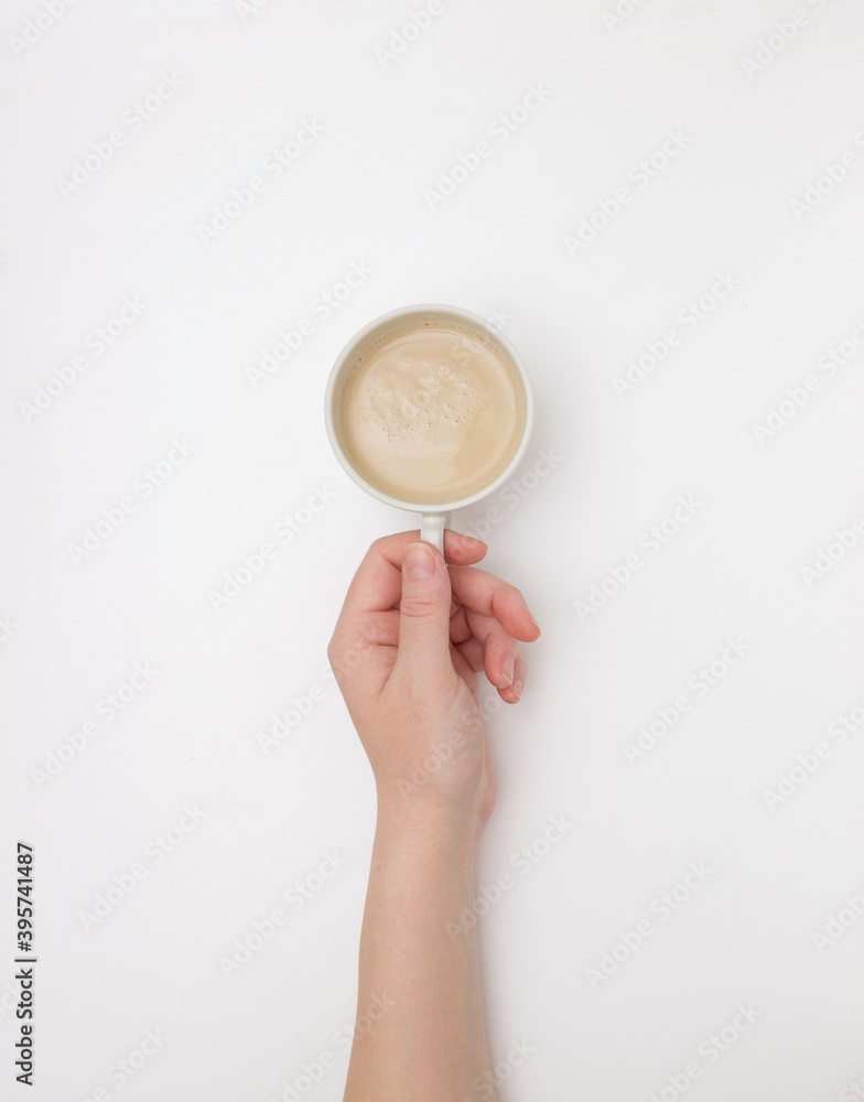 Fototapeta premium Women's hands hold a white Cup of cappuccino or cocoa. The view from the top.