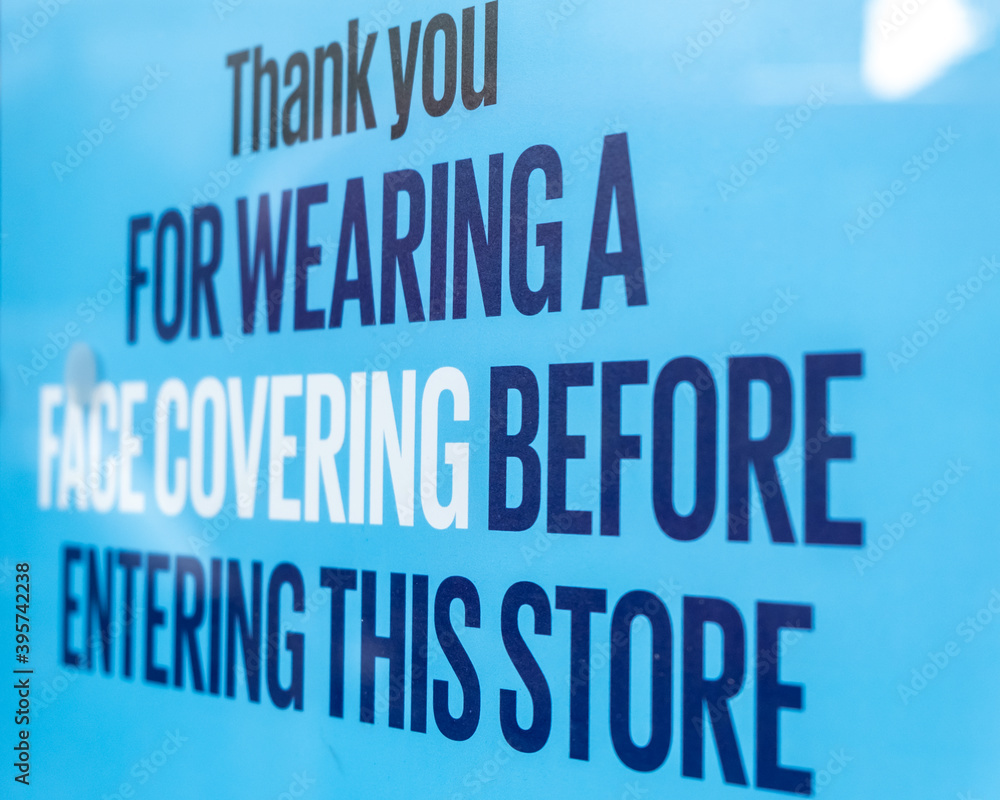 A close up of a sign on a shop window thanking customers for wearing a face covering when entering a shop