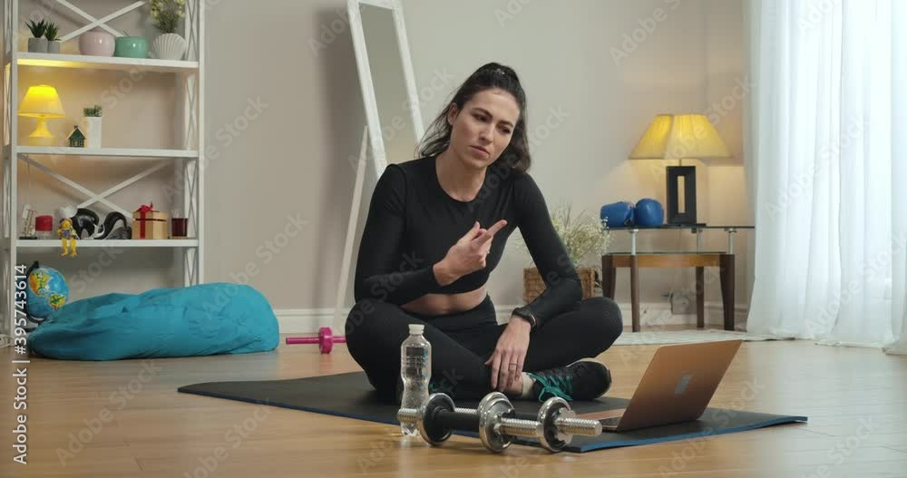 Smiling beautiful Caucasian sportswoman chatting online after training at home. Slim young woman sitting on exercise mat and talking at laptop selfie camera after workout. Cinema 4k ProRes HQ. Smiling beautiful Caucasian sportswoman chatting online after training at home. Slim young woman sitting on exercise mat and talking at laptop selfie camera after workout. Cinema 4k ProRes HQ.