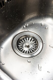 Stainless metal kitchen sink and drainage close up shot wet with water drops