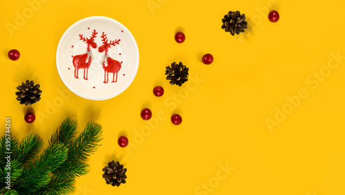 Christmas composition  decorative tableware  cones  berries  fir branches  yellow background with copy space  banner