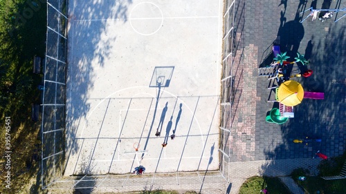 aerial view of street basketball court and children playground. kids are playing football at the sunset.