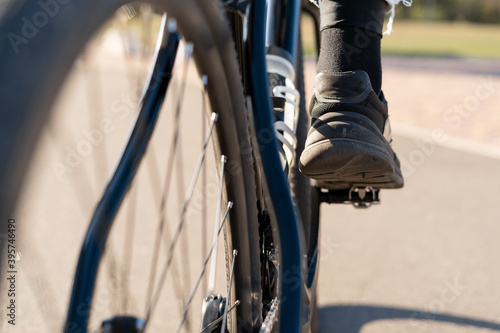 Cropped shot of man in sneakers riding a bicycle, feet on pedals.