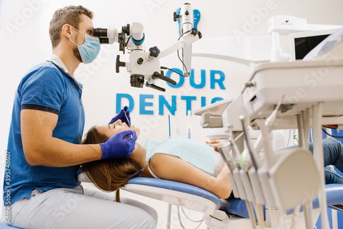 A dentist looking to the microscope at the patient's teeth
