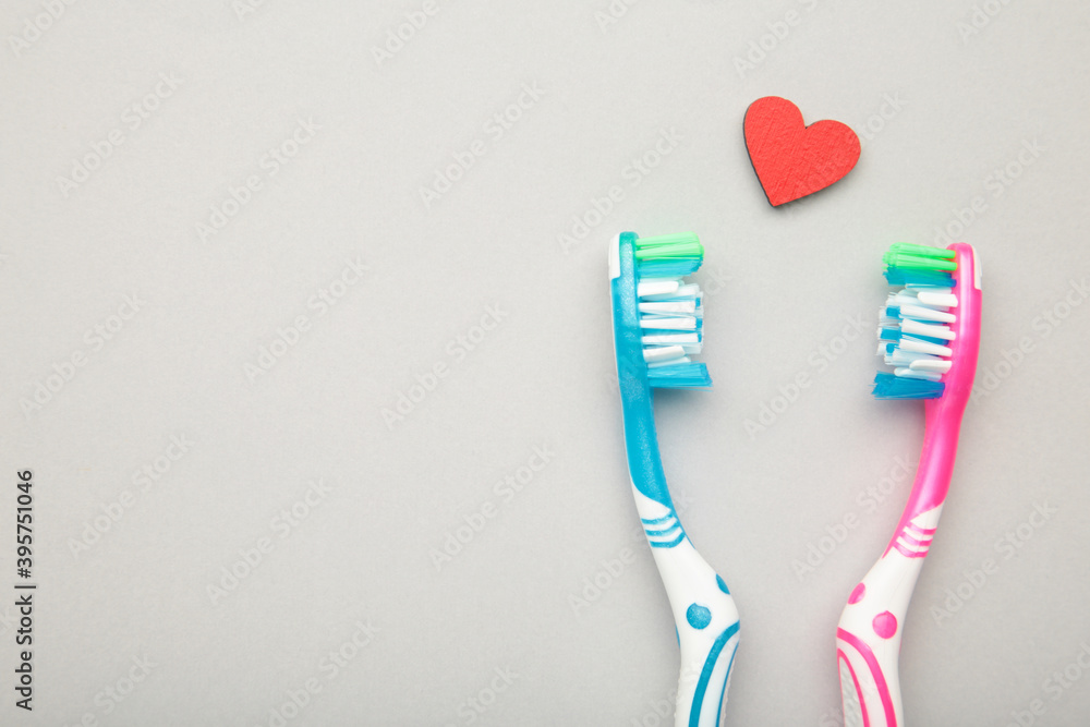 Two toothbrushes with heart on grey background. Man and woman teeth hygiene. Living together. Love concept. Two toothbrushes with heart on grey background. Man and woman teeth hygiene. Living together. Love concept.