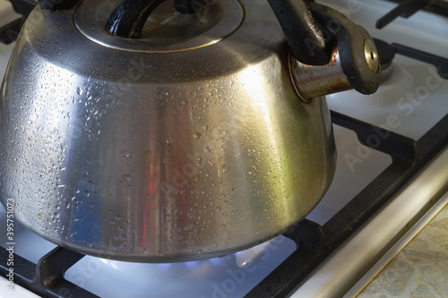 Water is heated in a steel kettle on a gas stove.