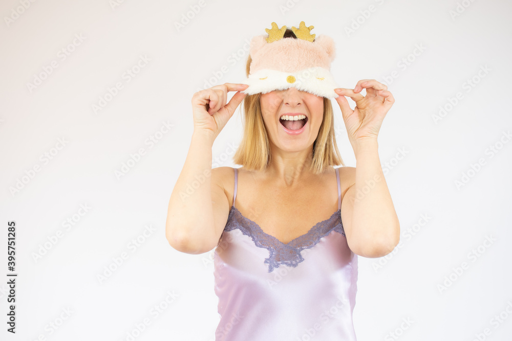 Gorgeous woman in mallow pajama posing on white background. Young lady in sleep mask playfully smiling. Gorgeous woman in mallow pajama posing on white background. Young lady in sleep mask playfully smiling.