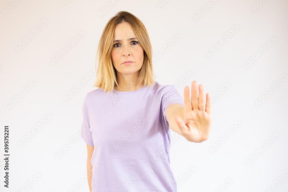 Portrait of a serious young woman standing with outstretched hand showing stop gesture isolated over white background Portrait of a serious young woman standing with outstretched hand showing stop gesture isolated over white background
