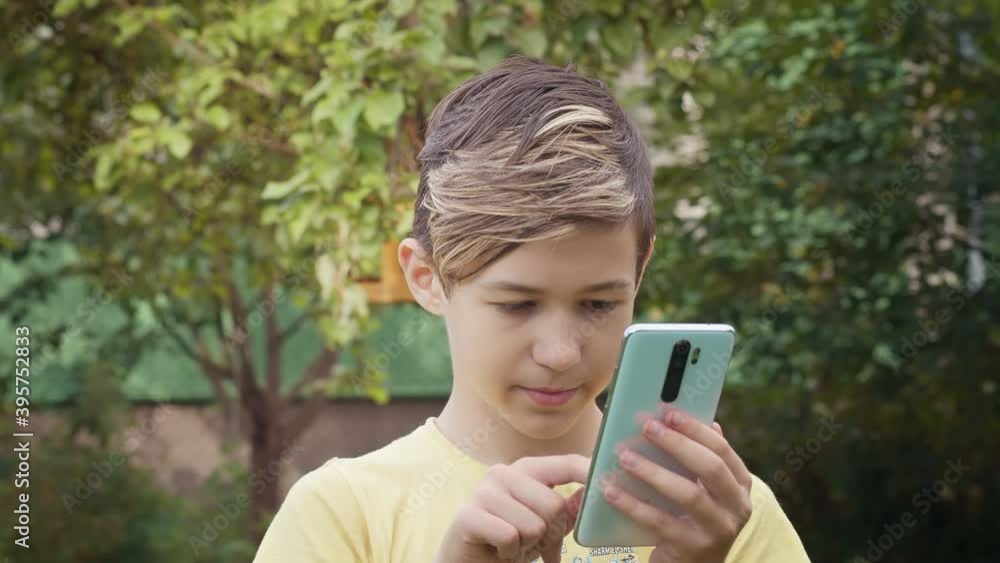 portrait of boy with stylish hairstyle uses phone outdoors portrait of boy with stylish hairstyle uses phone outdoors