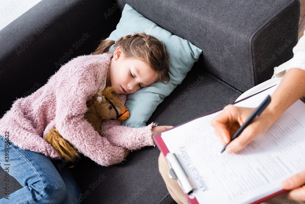 little girl lying on sofa with toy while telling problem to psychologist, stock image little girl lying on sofa with toy while telling problem to psychologist, stock image
