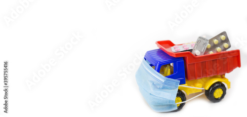 A toy car in a mask carries medicines on a white background, banner space for text