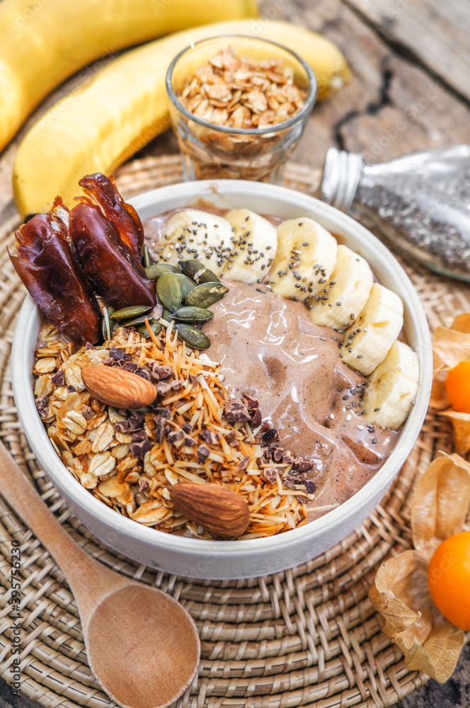 Close up chocolate hazelnut smoothie bowl topped with sliced banana, shredded coconut, chopped chocolate and seeds for healthy vegan vegetarian. Close up chocolate hazelnut smoothie bowl topped with sliced banana, shredded coconut, chopped chocolate and seeds for healthy vegan vegetarian.