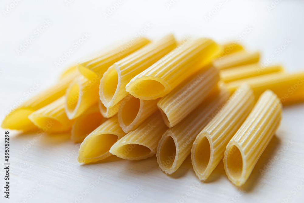 Pasta; raw Penne Rigate, on a white wooden surface. Pasta; raw Penne Rigate, on a white wooden surface.