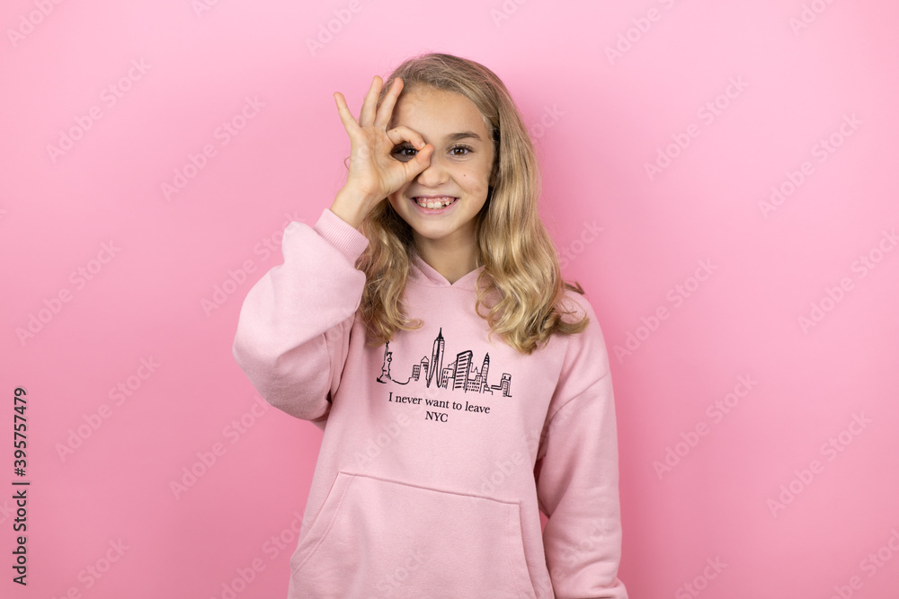 Young beautiful child girl standing over isolated pink background doing ok gesture shocked with smiling face, eye looking through fingers Young beautiful child girl standing over isolated pink background doing ok gesture shocked with smiling face, eye looking through fingers
