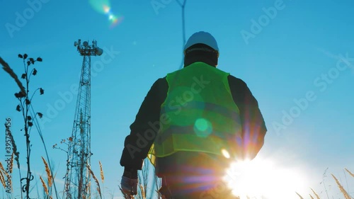 Silhouette engineer working on satellite dish telecom network on telecommunication tower in sunset. photo