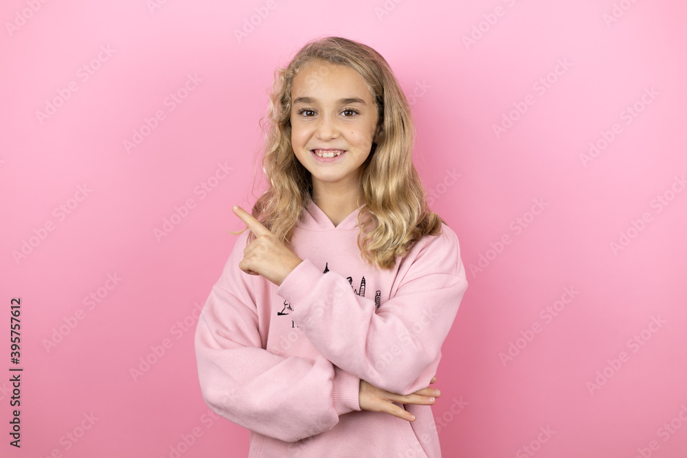 Young beautiful child girl standing over isolated pink background smiling confident pointing with hand and finger to the side Young beautiful child girl standing over isolated pink background smiling confident pointing with hand and finger to the side