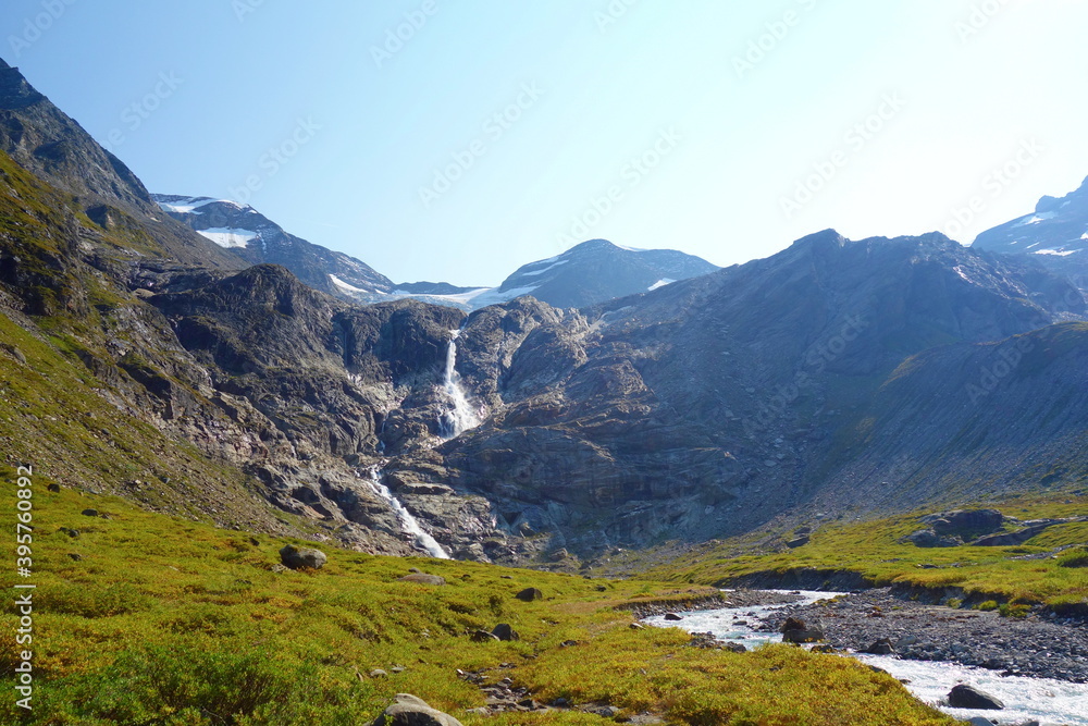 Fototapeta premium Waterfall flowing to the Reservoir Mooserboden embedded in the impressive mountains of the Hohe Tauern near Kaprun, Austria.