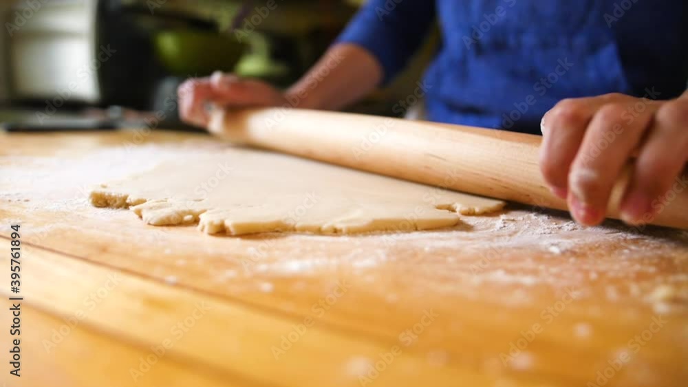 Hands rolling dough with rolling pin on floured surface Hands rolling dough with rolling pin on floured surface