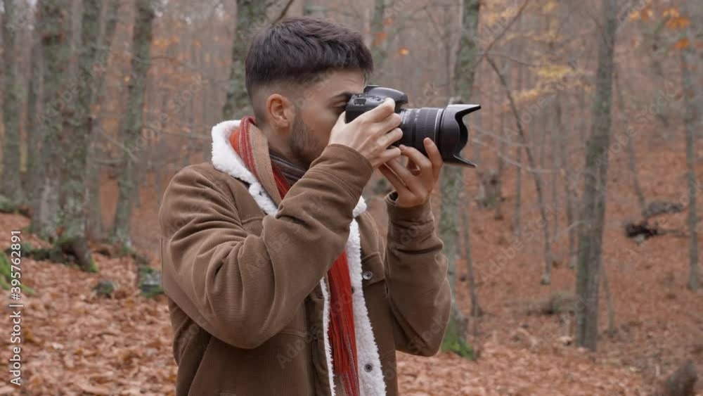 Medium shot Caucasian boy in forest with red and orange autumn leaves photographing with a professional camera Medium shot Caucasian boy in forest with red and orange autumn leaves photographing with a professional camera