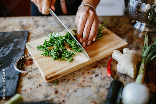 Fototapeta Naklejka Na Ścianę i Meble -  Woman chef prepares food and cuts greens, parsley, red pepper and onion.