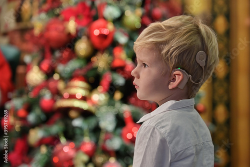 Obraz na płótnie A Boy with Cochlear Implants and Christmas tree w salonie
