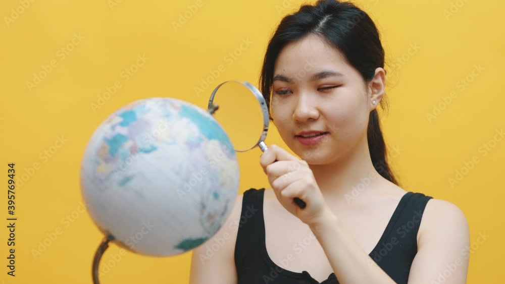 Young asian woman looking at the globe through the magnifier. High quality 4k footage Young asian woman looking at the globe through the magnifier. High quality 4k footage
