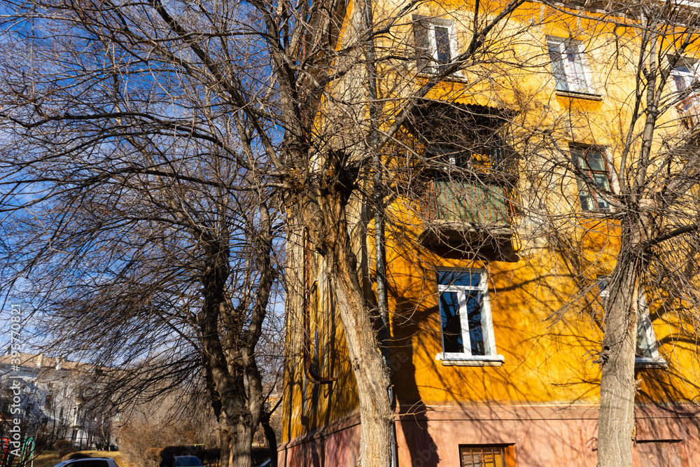 bare branches of trees in autumn and part of a yellow large old house against the blue sky. bare branches of trees in autumn and part of a yellow large old house against the blue sky.