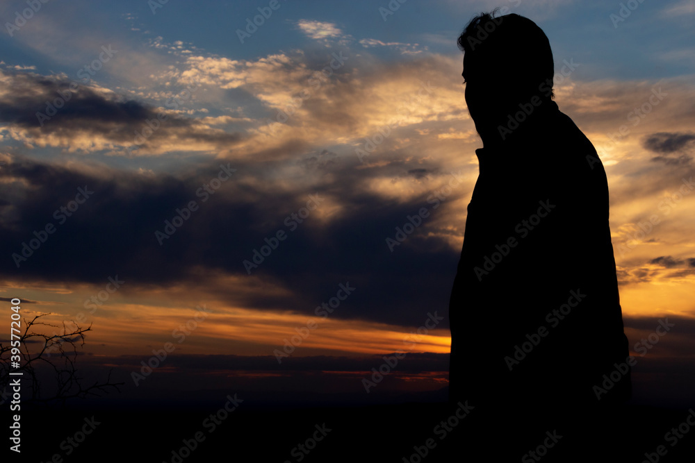 Men raise their arms in sunrise,Landscape with silhouette of a standing happy man with backpack and raised-up arms on the mountain peak on the background of cloudy sky at colorful sunset Men raise their arms in sunrise,Landscape with silhouette of a standing happy man with backpack and raised-up arms on the mountain peak on the background of cloudy sky at colorful sunset