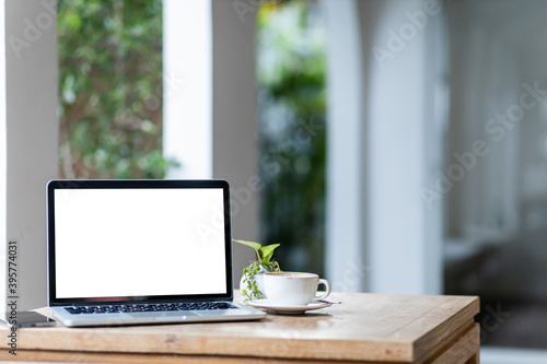Mockup of laptop computer with empty screen with coffee cup and smartphone on table of the coffee shop background,White screen