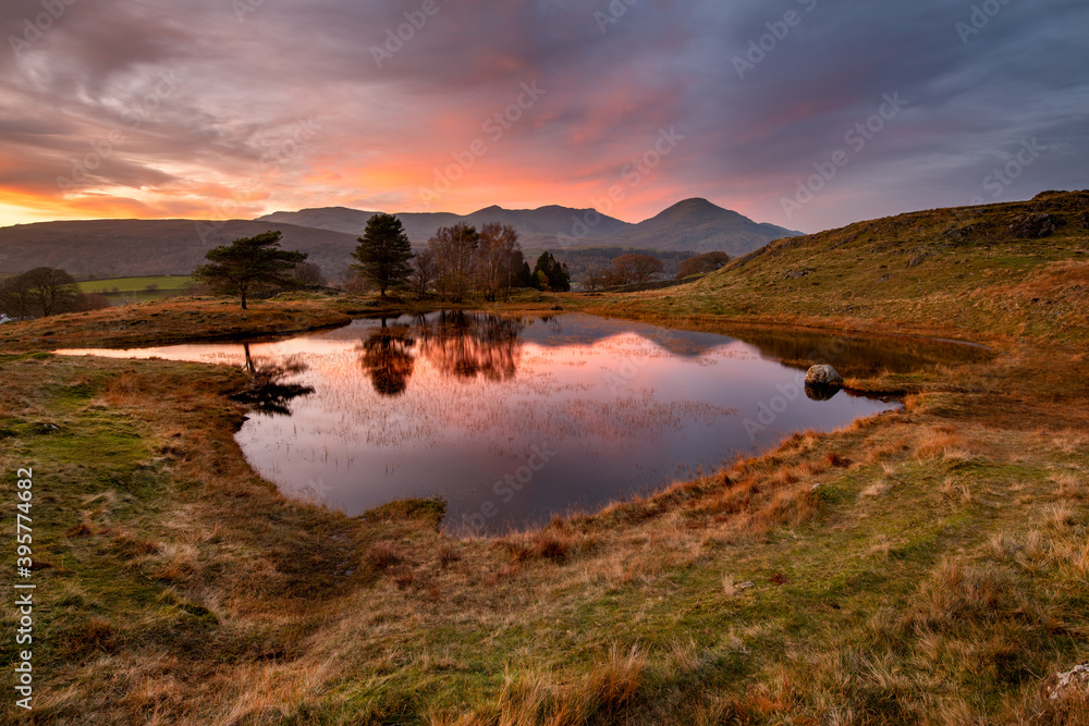 Sunset view of mountain tarn with reflections at Kelly Hall Tarn in the English Lake District.